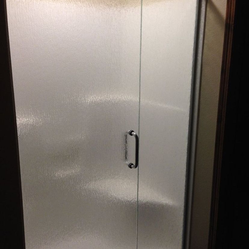 Frosted glass shower door with a silver handle.