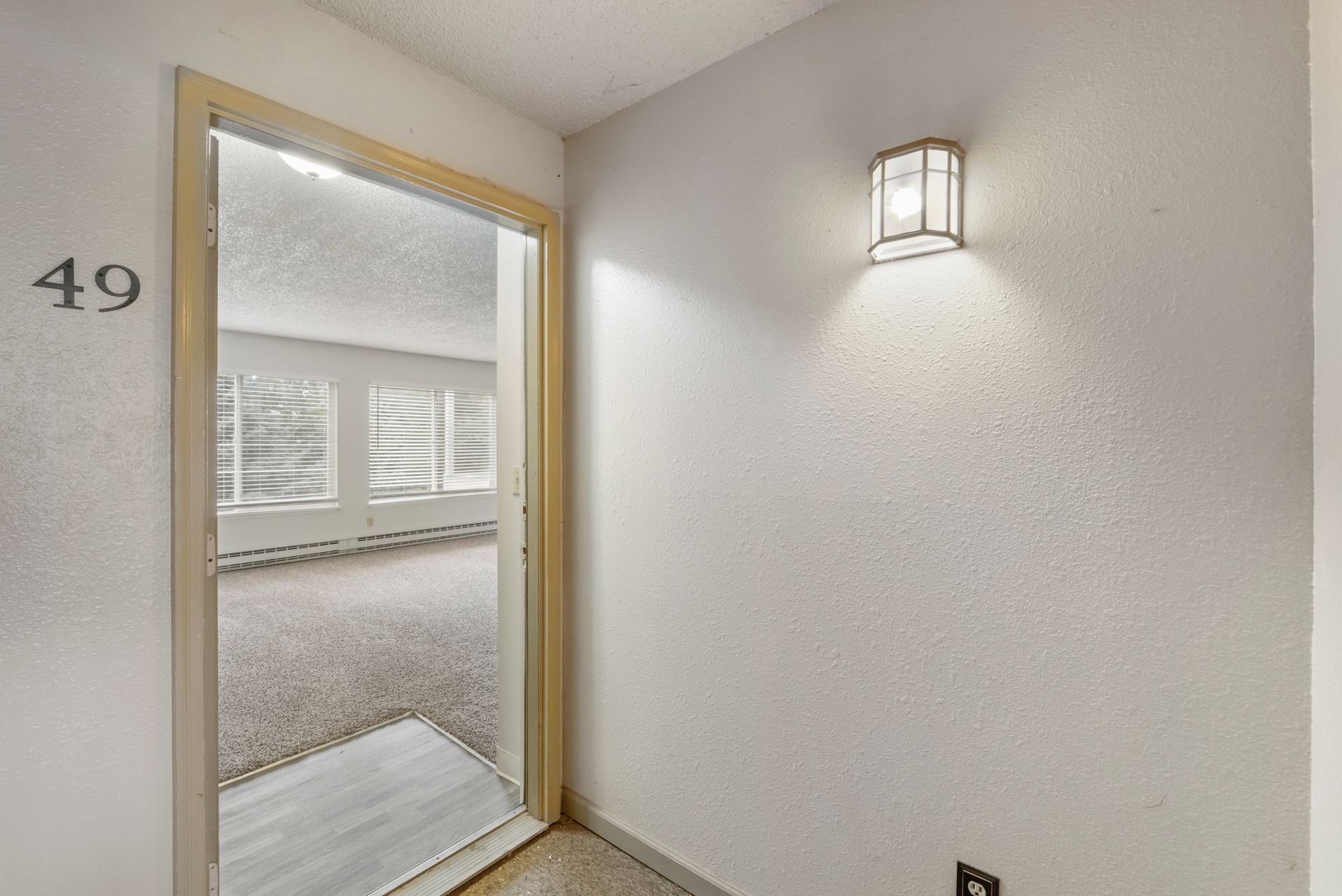 A hallway with a door and a light on the wall.