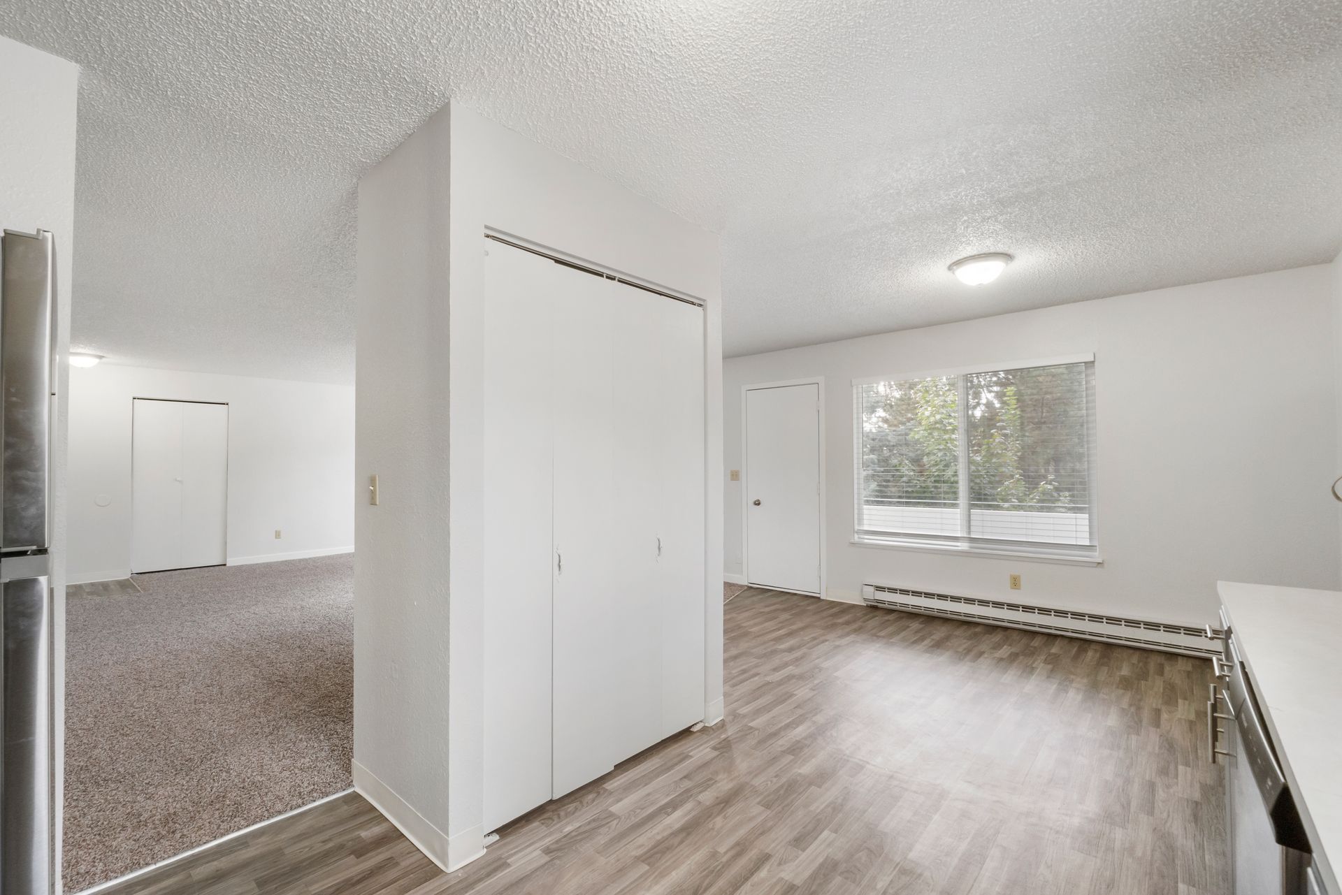 A living room with hardwood floors , white walls and a window.