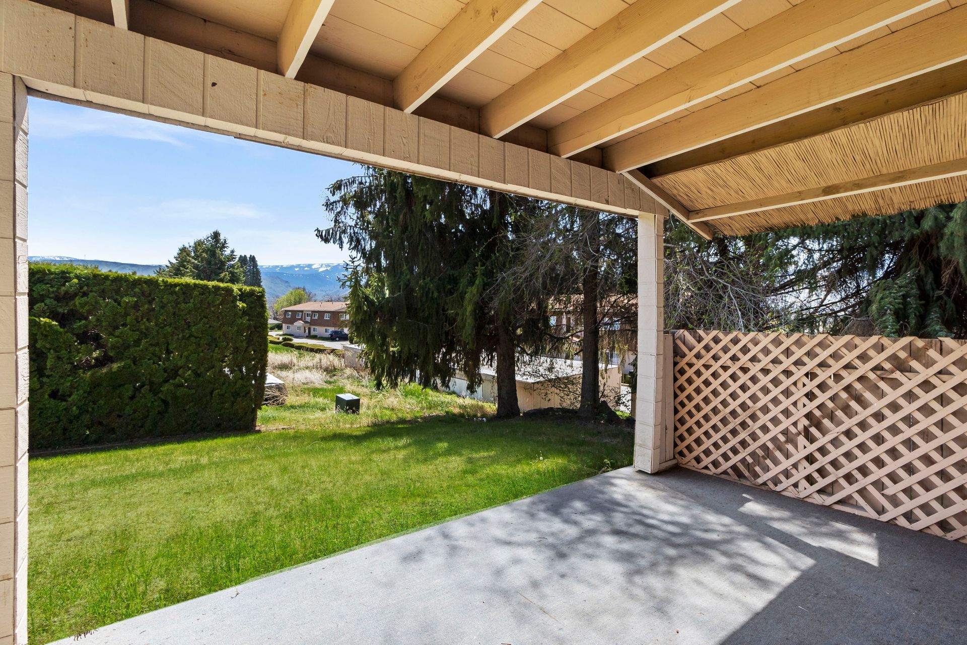 A covered patio with a view of a lush green yard
