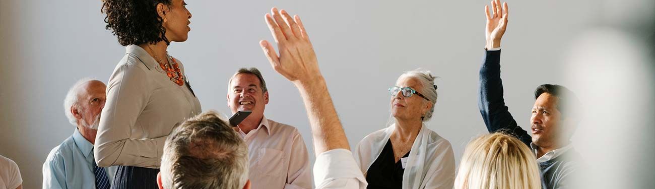 A group of people are raising their hands to answer a question.