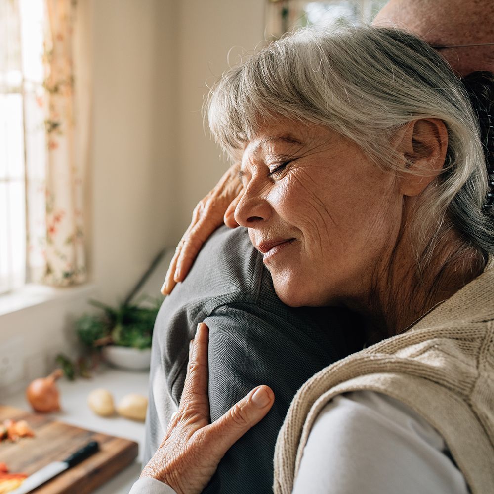 Two grey haired adults hugging each other