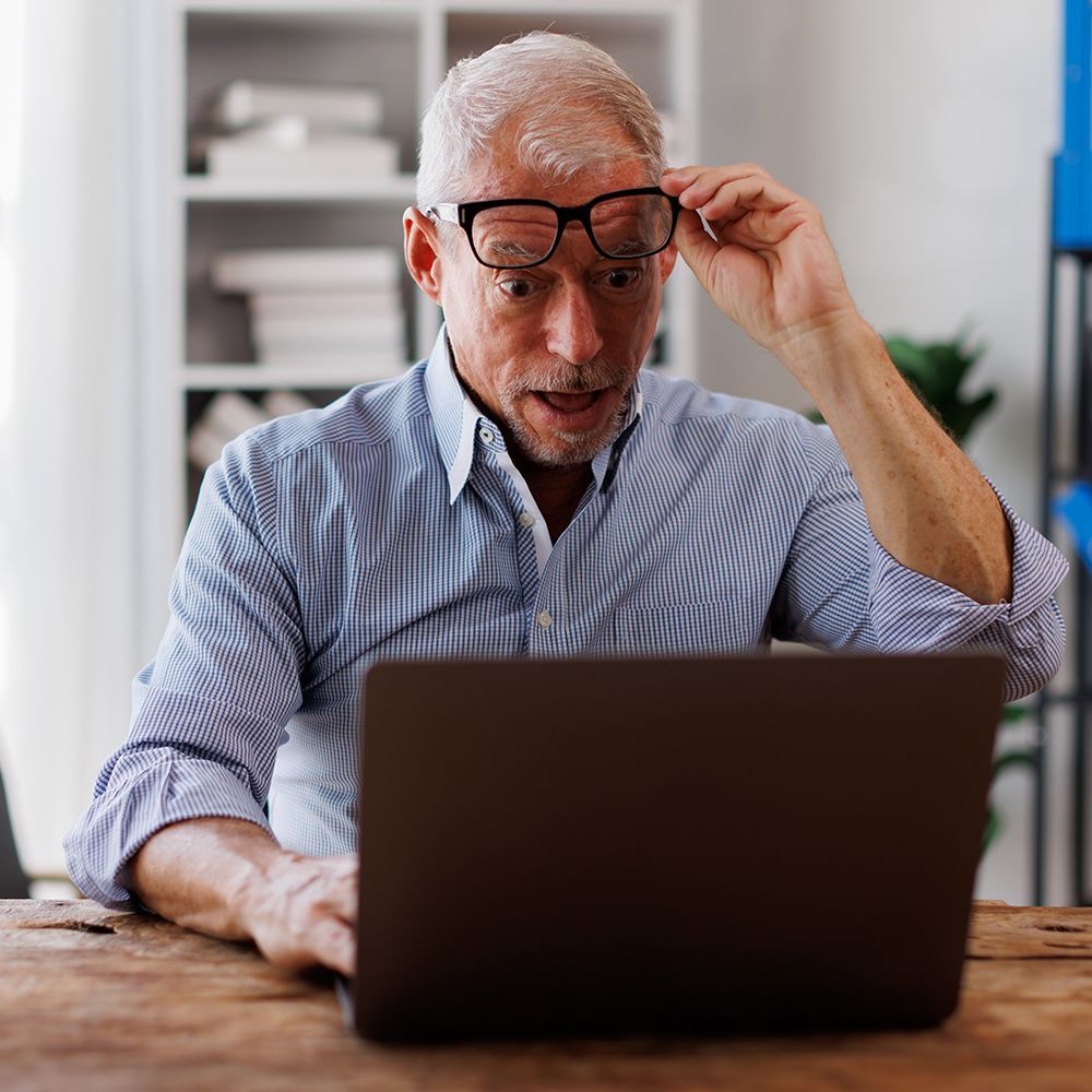 Man looking happy and surprised while looking at his laptop