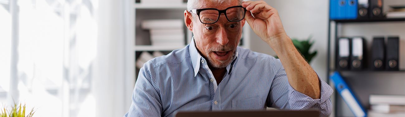Man looks happily surprised at his laptop screen 