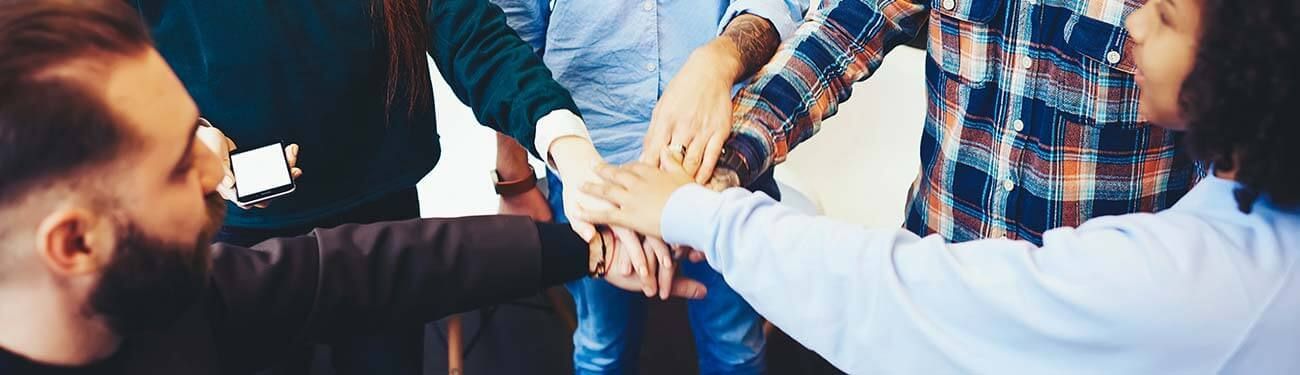 A group of people are putting their hands together in a circle.