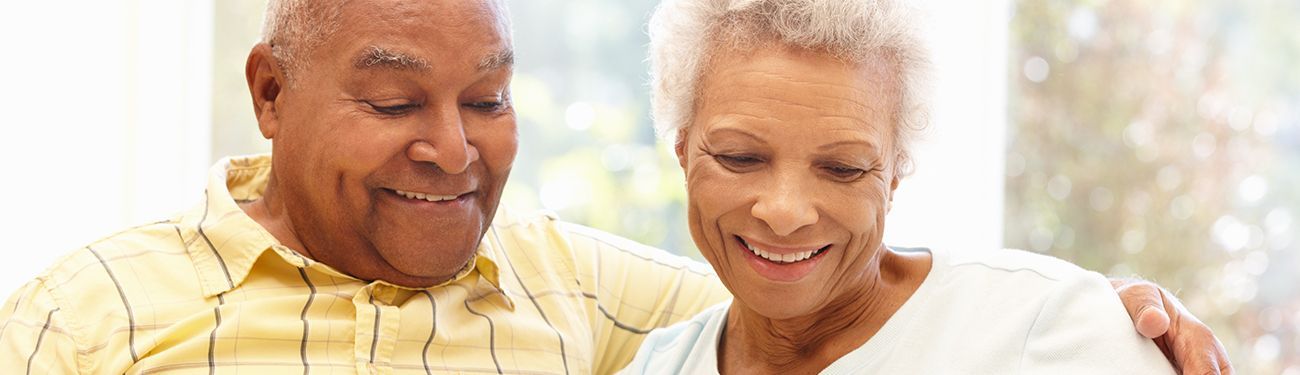 Two senior citizens on a couch reading a newsletter