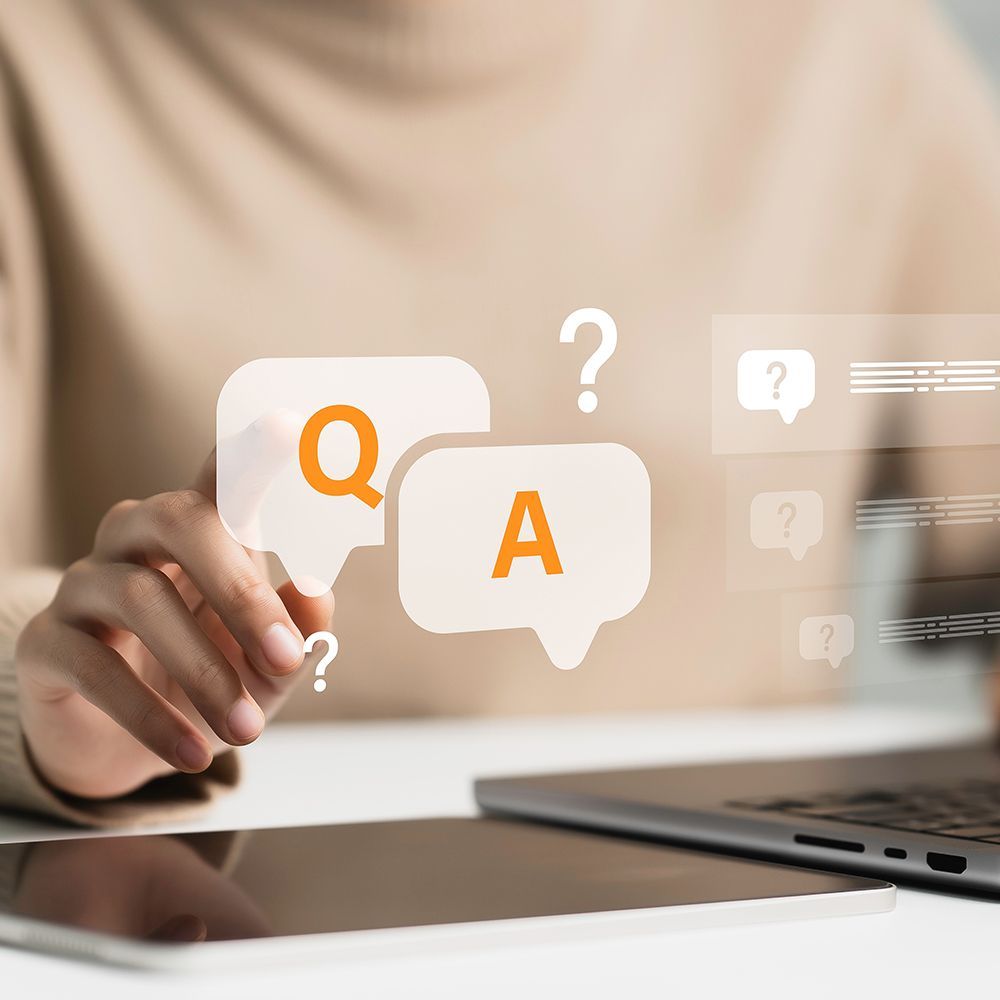 Hand touching floating Q and A speech bubbles above a tablet on a desk