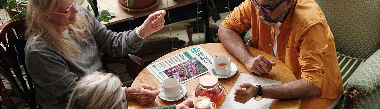 People sitting around a table with a newsletter laying on it.