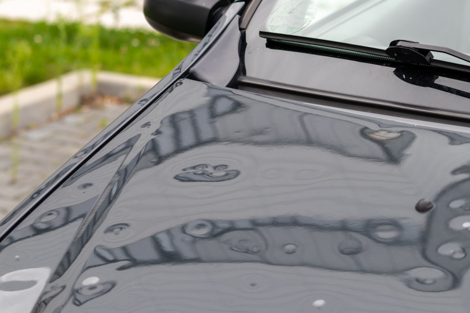 Black Jeep SUV with extensive hail damage on hood and windshield.