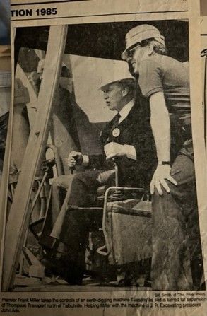 a black and white photo of two men in hard hats talking to each other .
