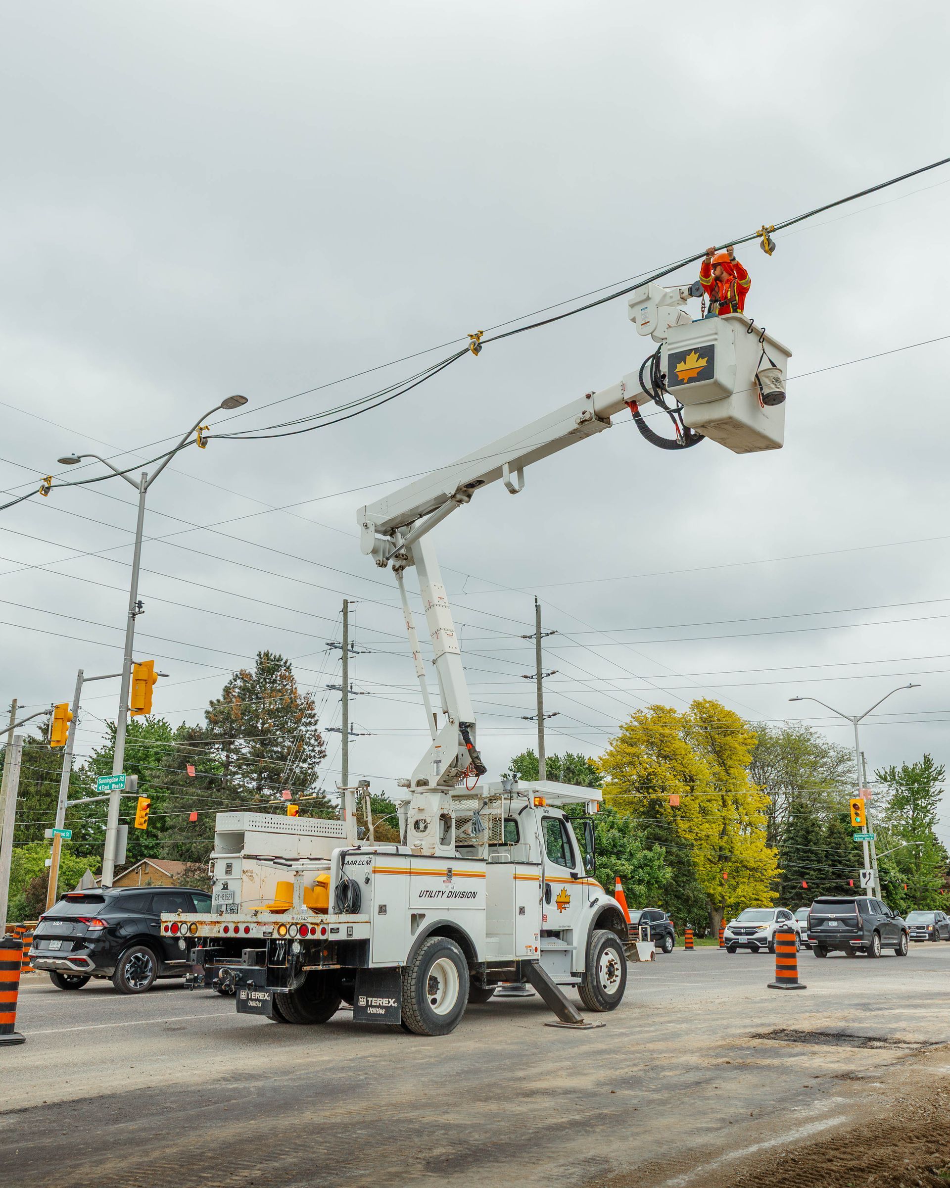 Two construction workers are working on a pole in the dirt.