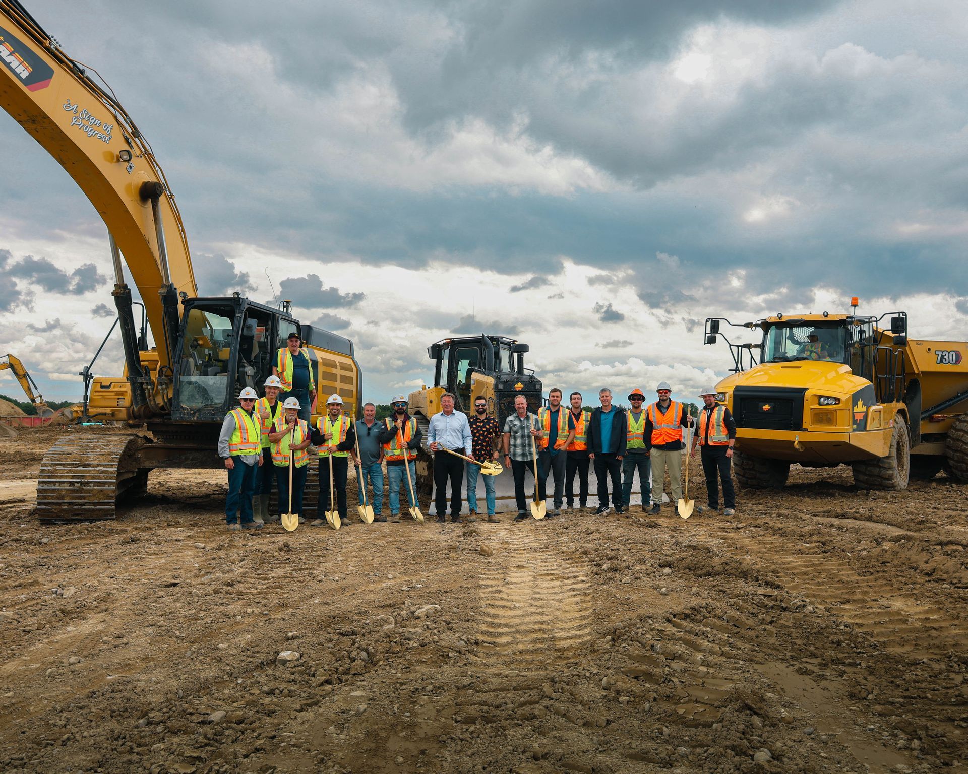 A group of construction workers are posing for a picture in front of a construction site.