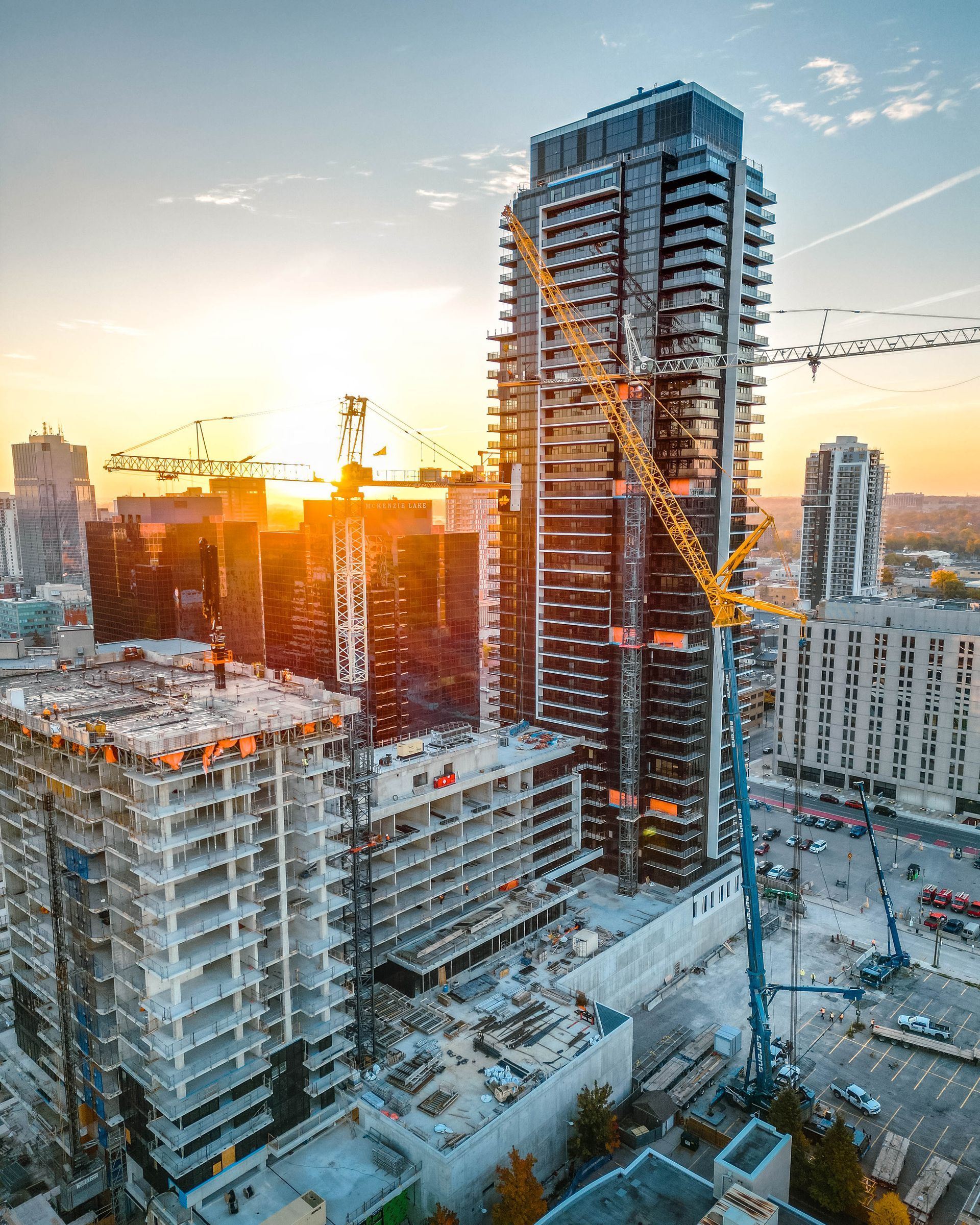 City skyline with high-rise buildings under construction at sunset, cranes visible.