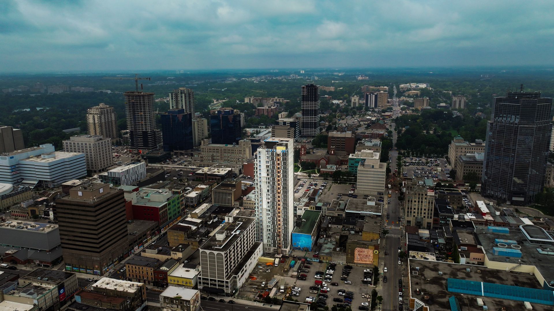 Aerial view of a city street lined with tall buildings under an overcast sky.