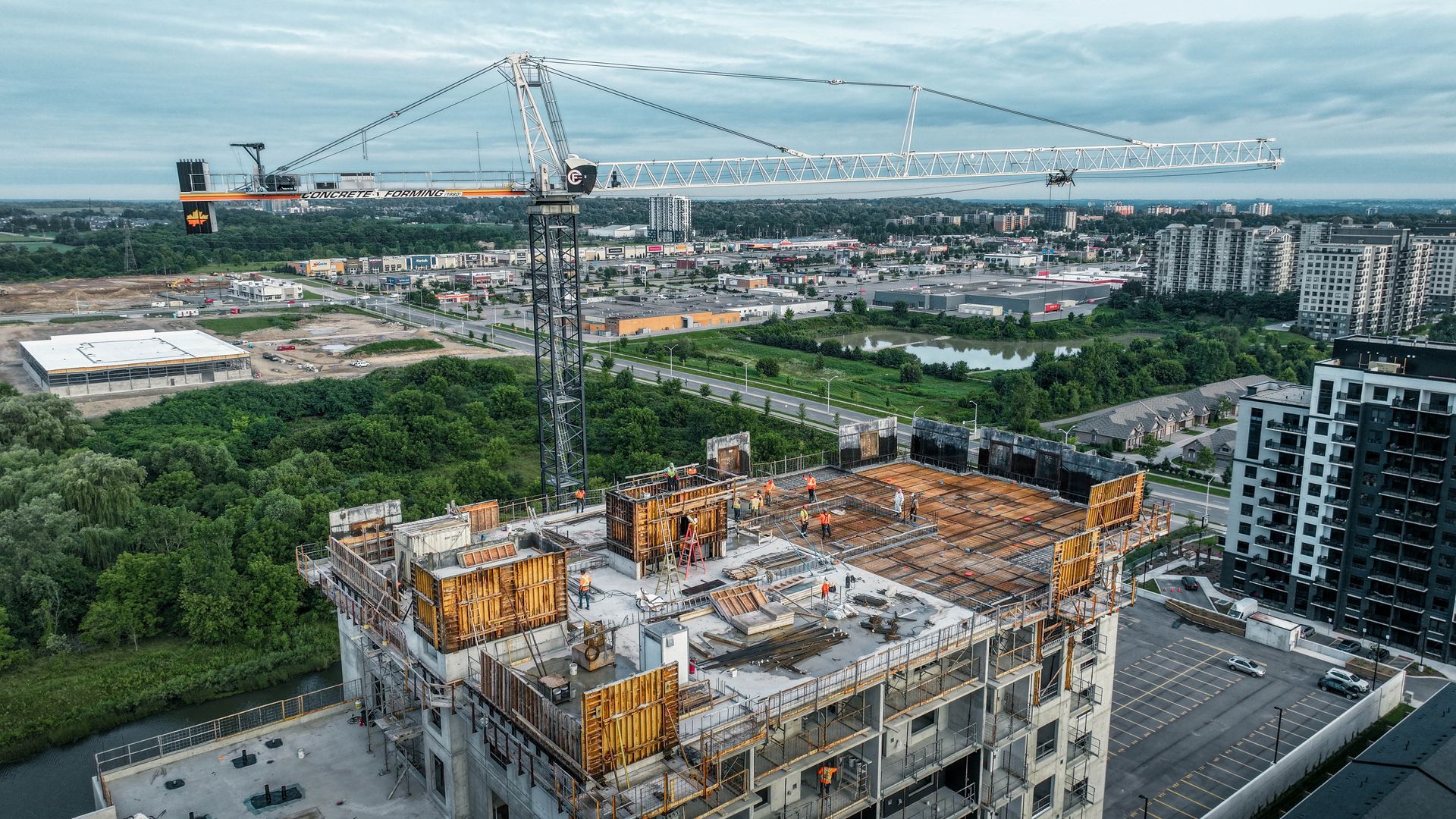 Construction site with a tower crane, partially built building with concrete structures. City in the background.