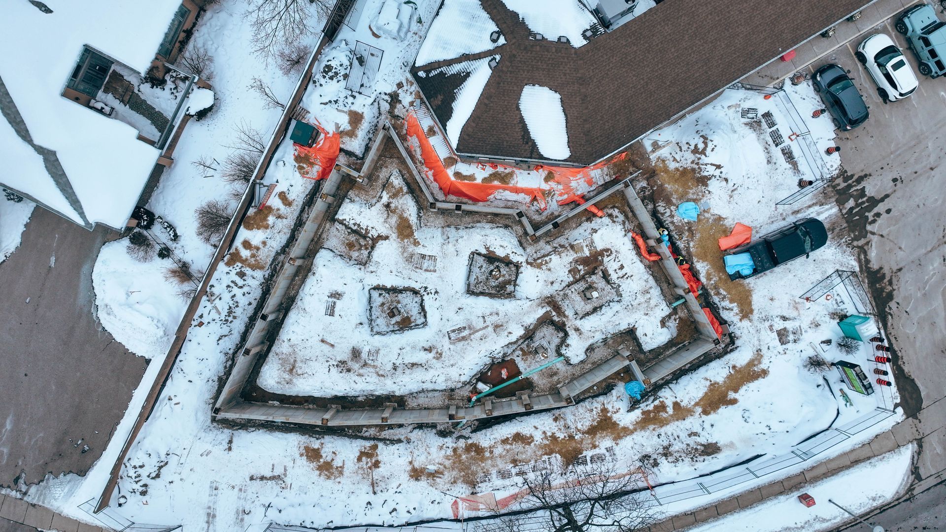 Overhead view of a snow-covered star-shaped fort with construction materials, in a partially snow-covered area.
