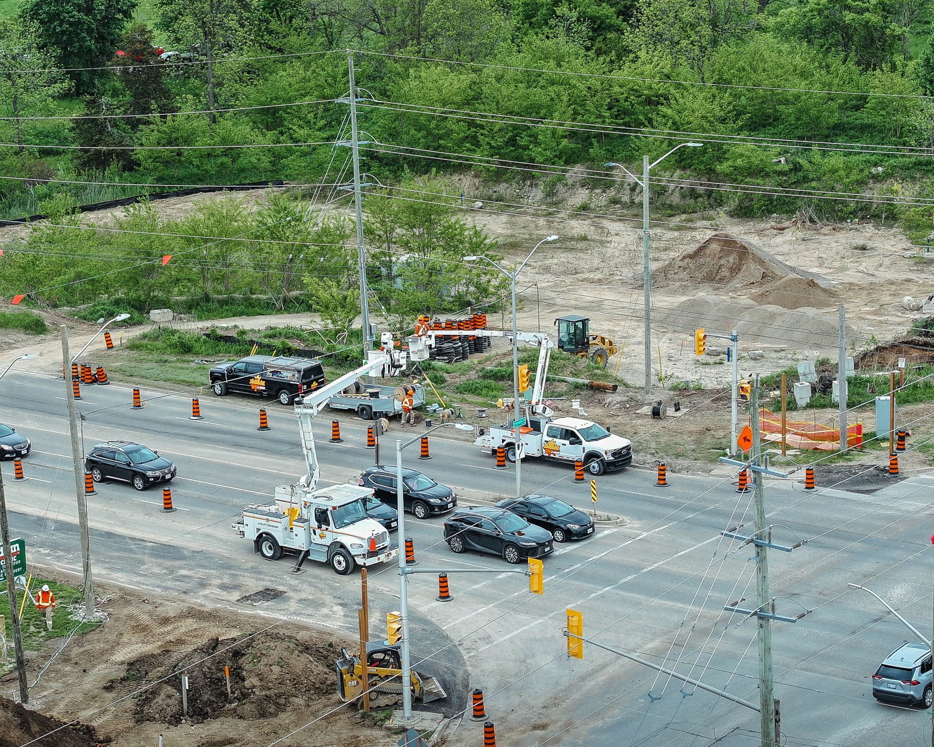 Road construction with several utility trucks and traffic cones on a multi-lane road.