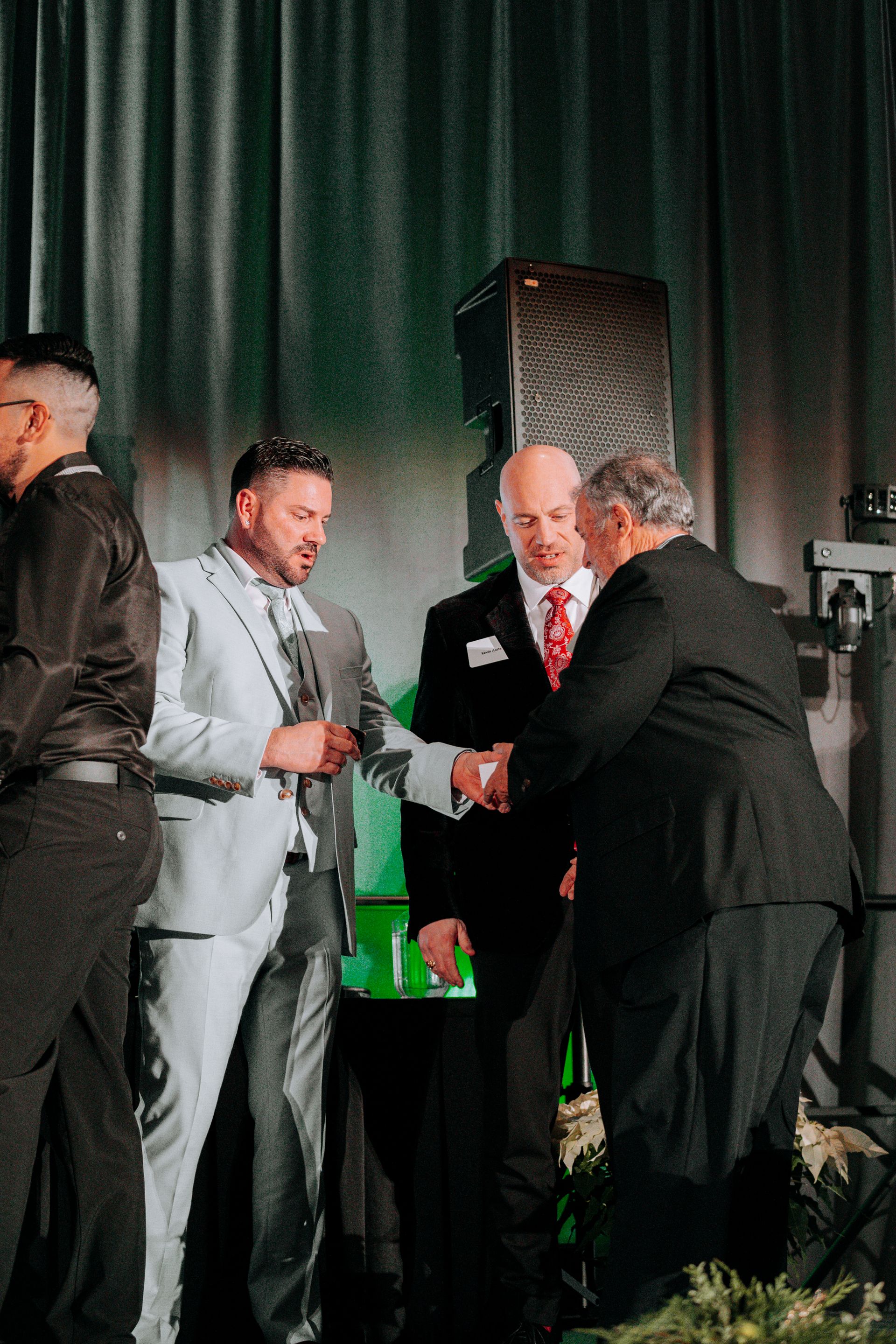 a group of men in suits are shaking hands on a stage .