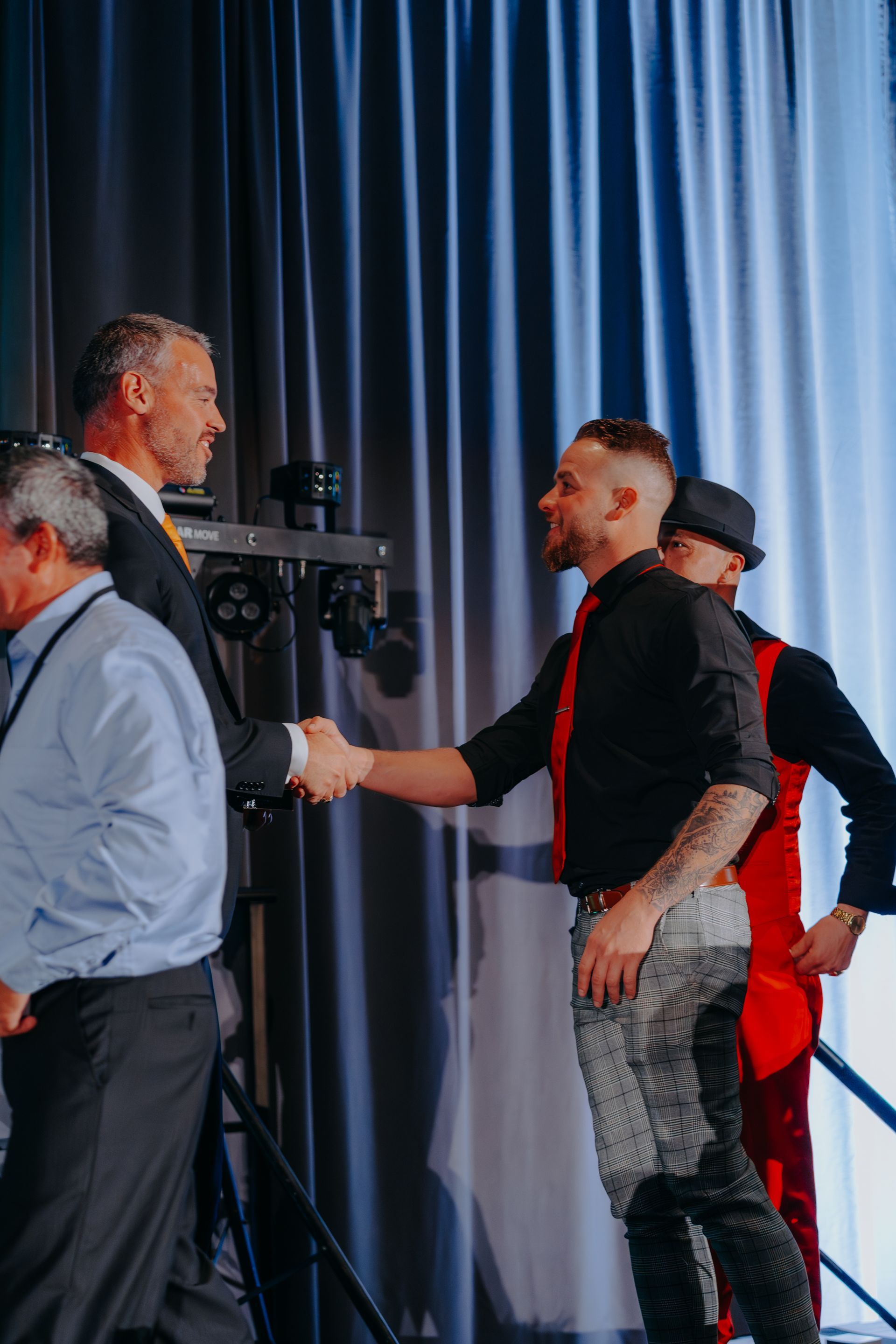 a group of men are shaking hands on a stage .
