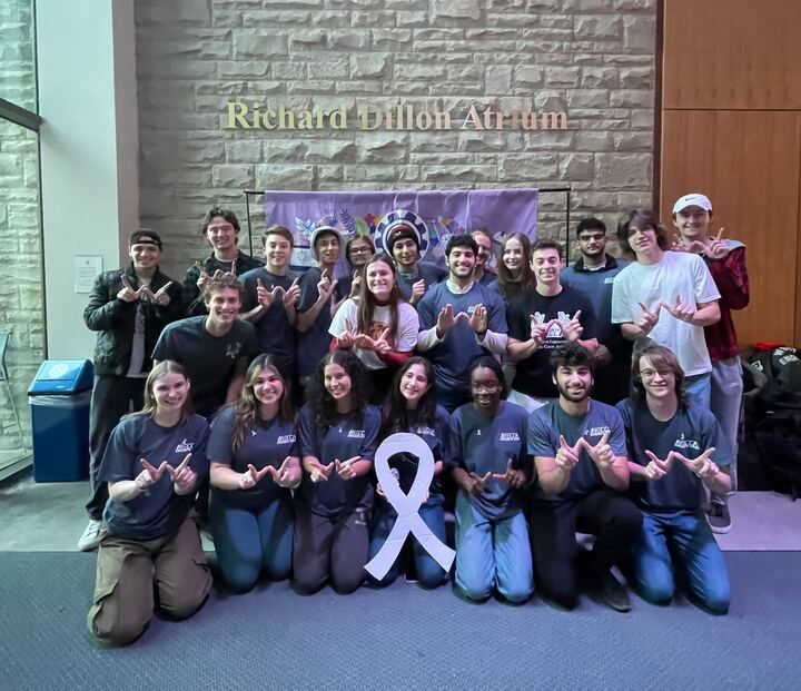 a group of people posing for a picture with a white ribbon