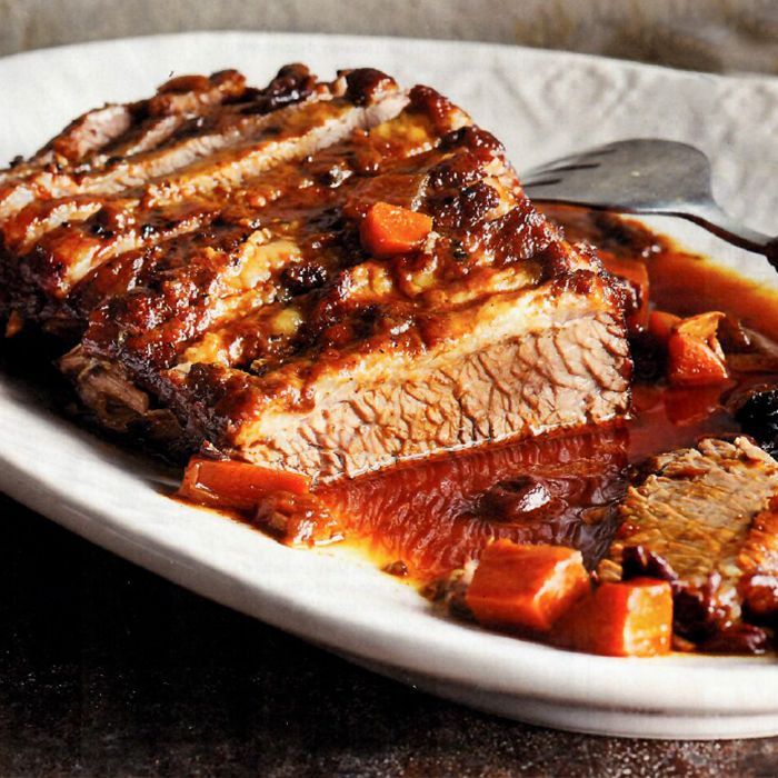 A white plate topped with meat and carrots with a fork