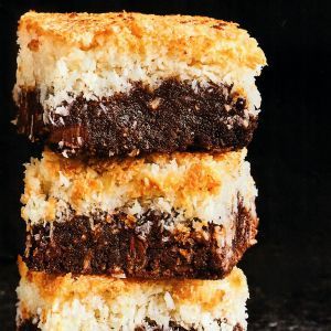 Three coconut brownies are stacked on top of each other.