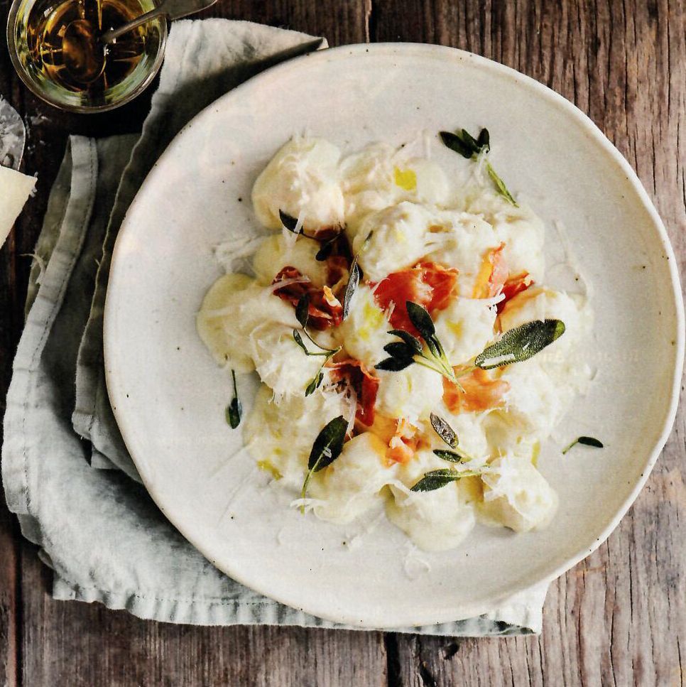 A white plate topped with noodles and sauce on a wooden table