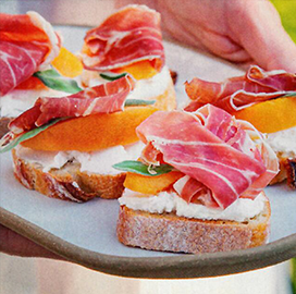 A person is holding a plate of food with meat and cheese on it