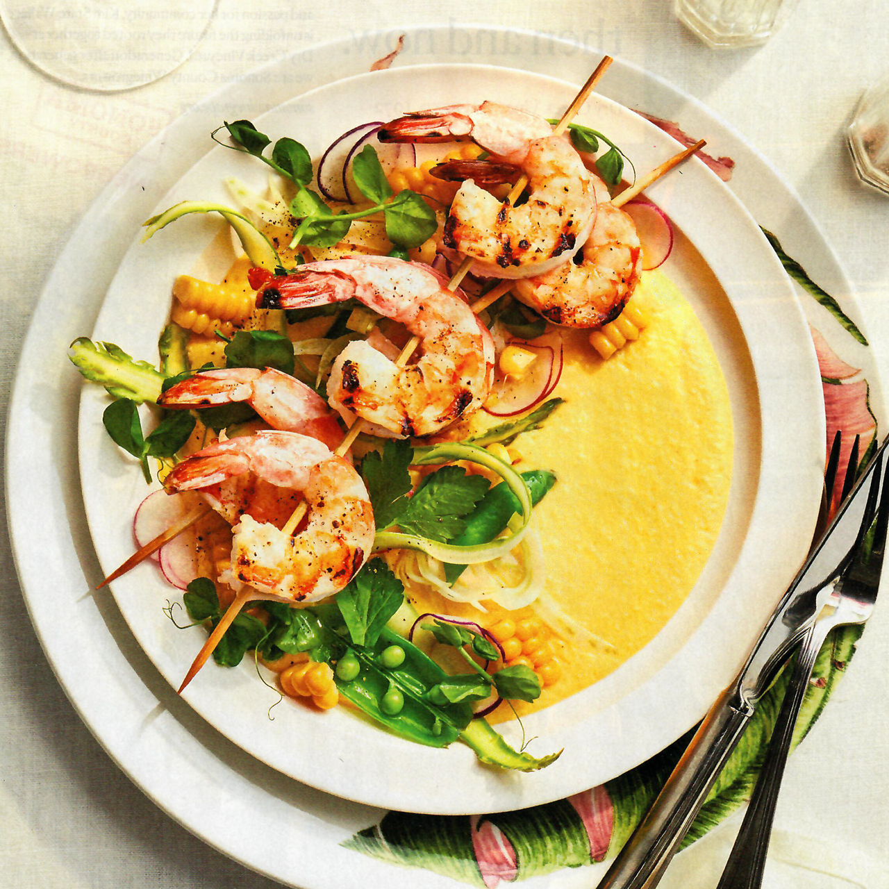 A plate of food with shrimp and vegetables on skewers