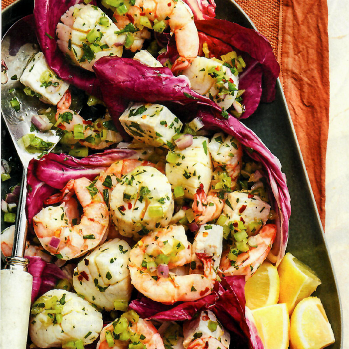 A tray of shrimp salad with lettuce and lemons
