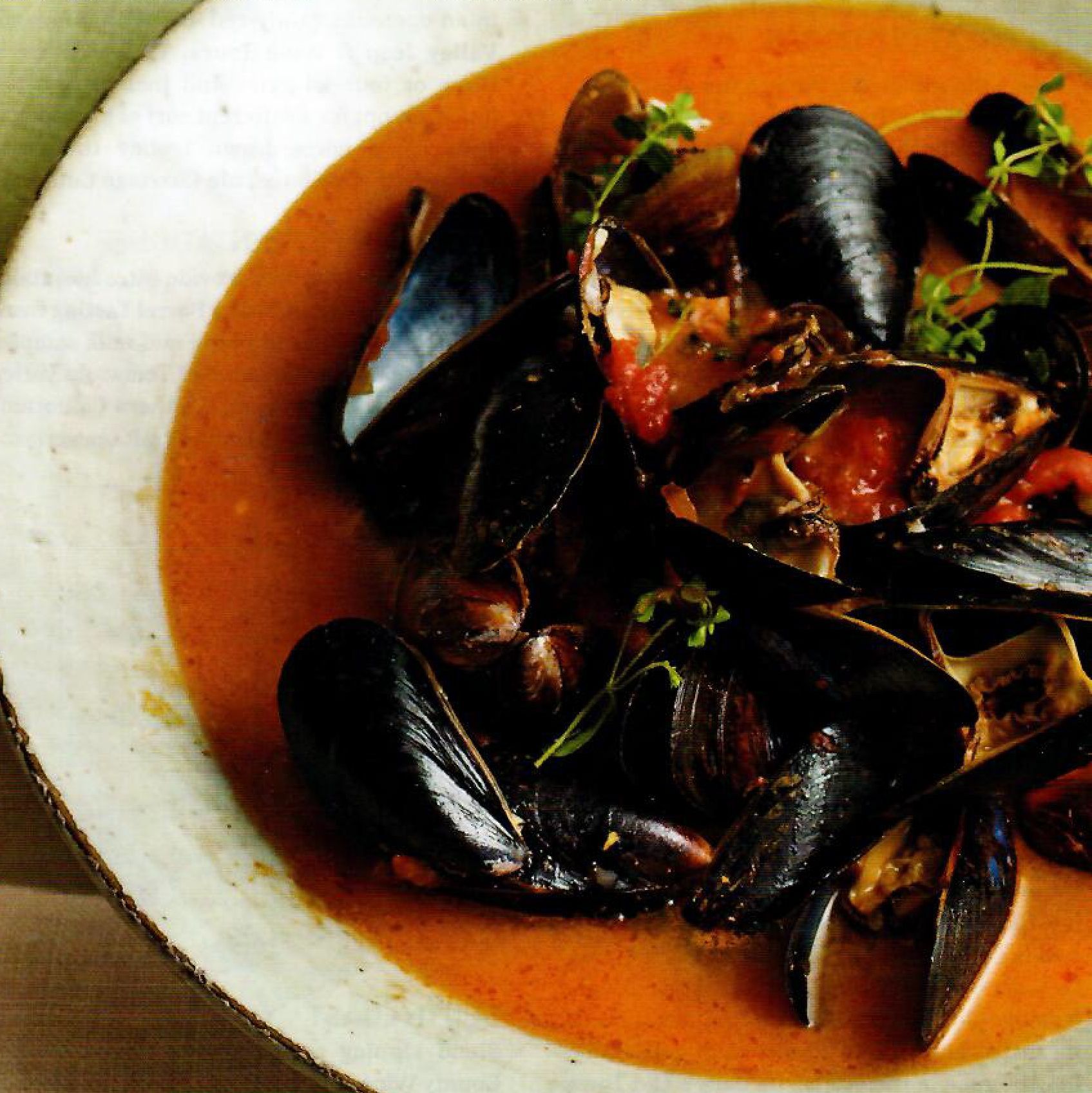 A close up of a bowl of mussels in a sauce