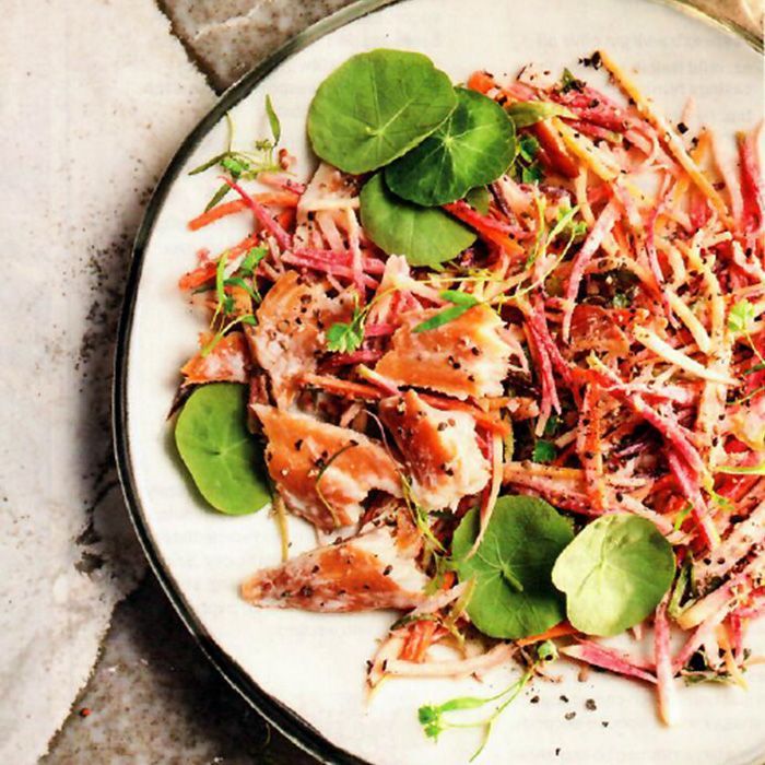A white plate topped with a salad of vegetables and meat