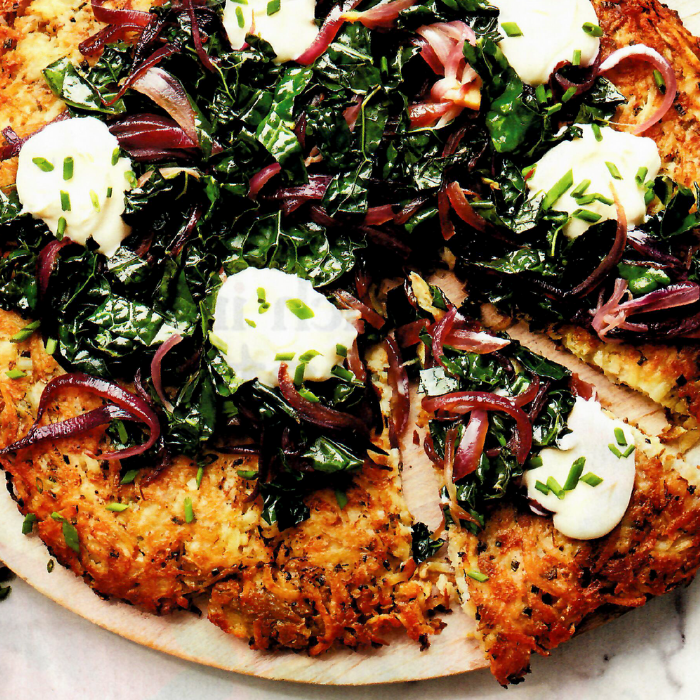 A pizza with spinach onions and sour cream on it