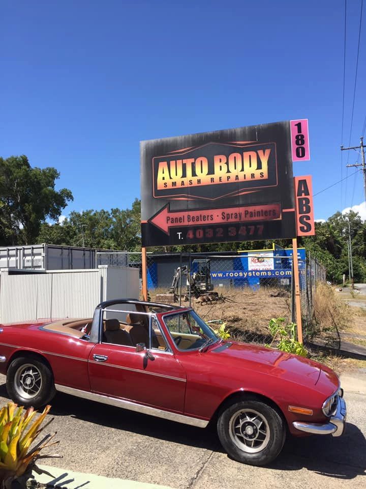 A Red Car Is Parked In Front Of A Sign That Says Auto Body — ABS Repairs in Manunda, QLD