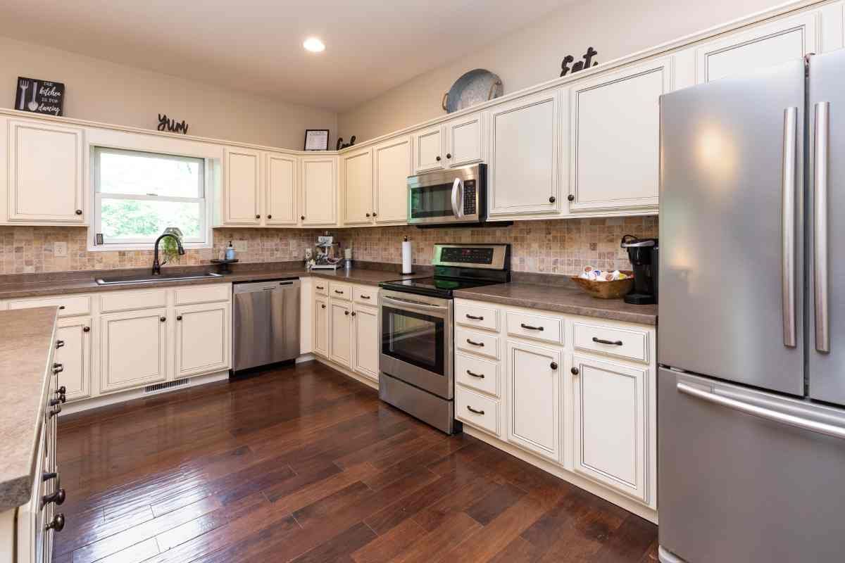 A sizable kitchen with white cabinets, wood floors, and a window at Blinded by Delight Window Coverings & Design near San Antonio and Boerne, Texas (TX)