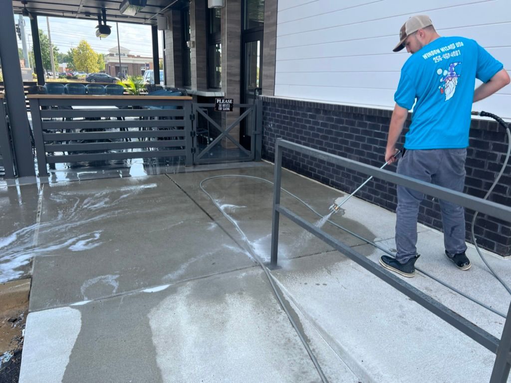 Worker in a blue shirt smoothing wet concrete beside a building and metal railing
