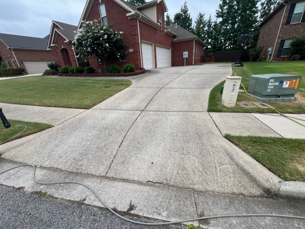 Steep concrete driveway leading to a brick suburban house with lawn and mailbox on the right