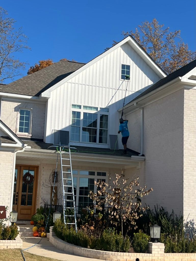 Worker on a roof repairing a white house with a ladder in front