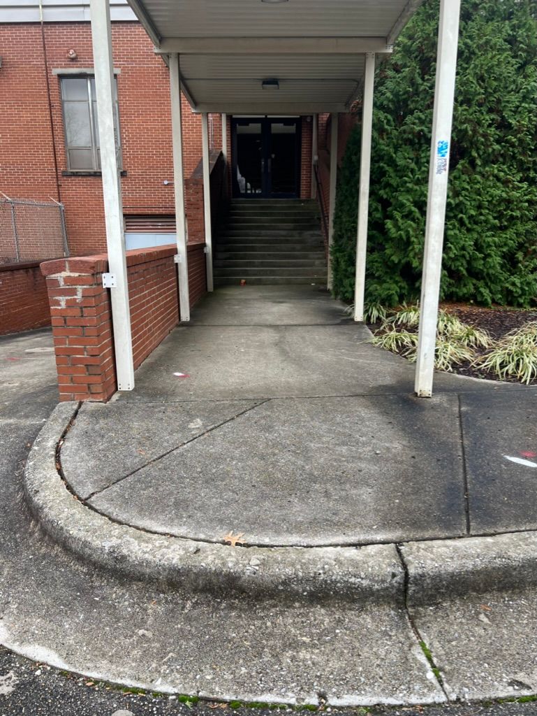 Covered walkway with ramp, stairs, and brick building entrance path