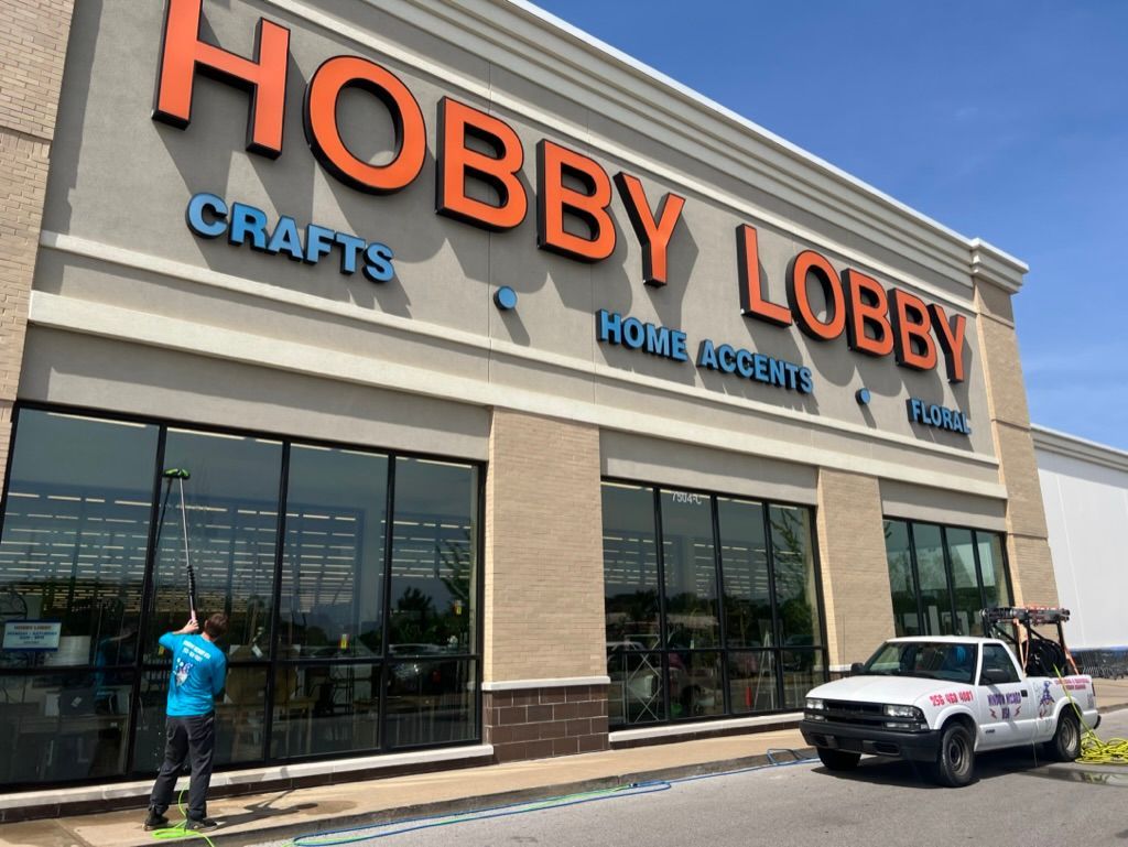 Hobby Lobby store exterior with large orange sign, glass windows, and a parked SUV out front
