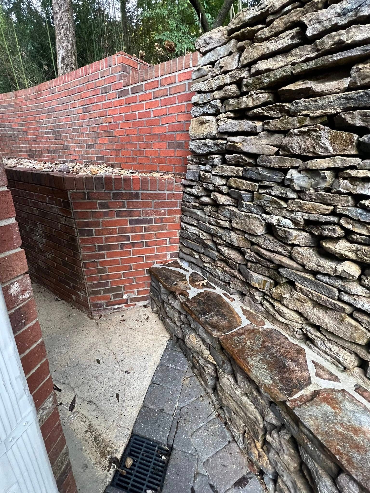 Brick and stone outdoor passage with a sloped wall and narrow concrete walkway