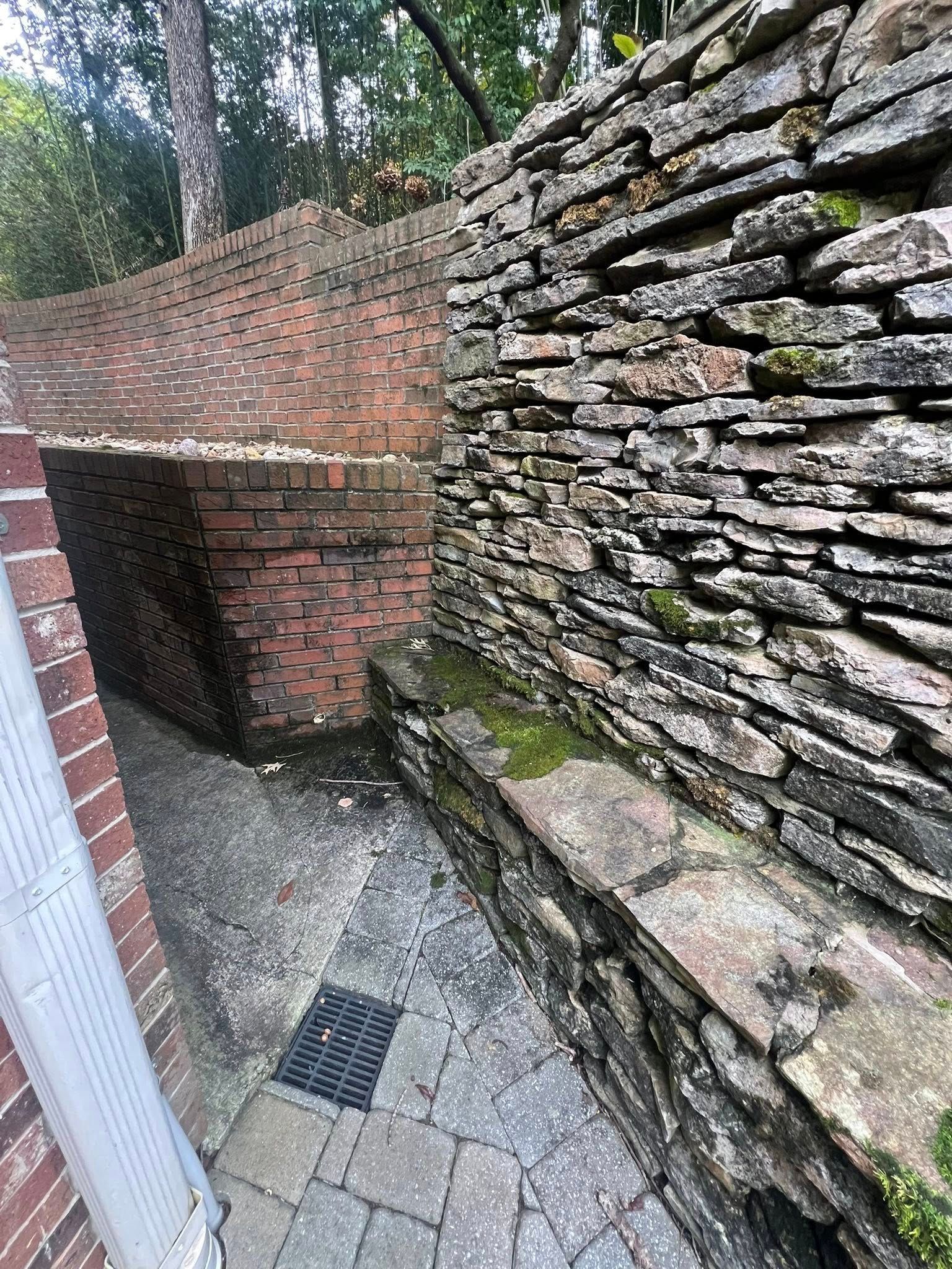 Stone stairway beside a brick wall and brick archway in a narrow outdoor passage, with mossy steps and paving.