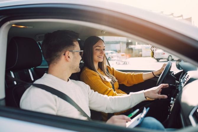 A man is teaching a woman how to drive a car.