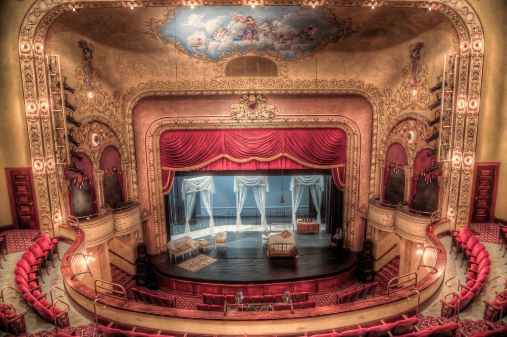 An empty theatre with red seats and a stage