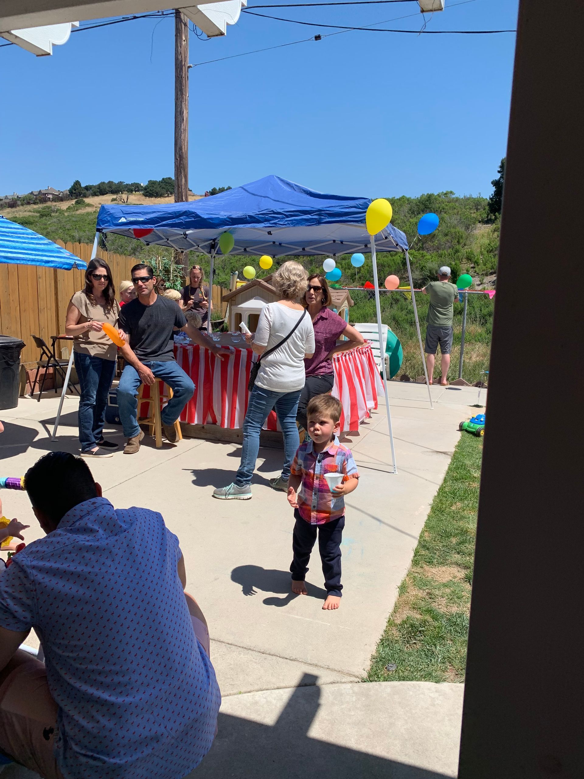 A little boy is standing in front of a group of people at a party