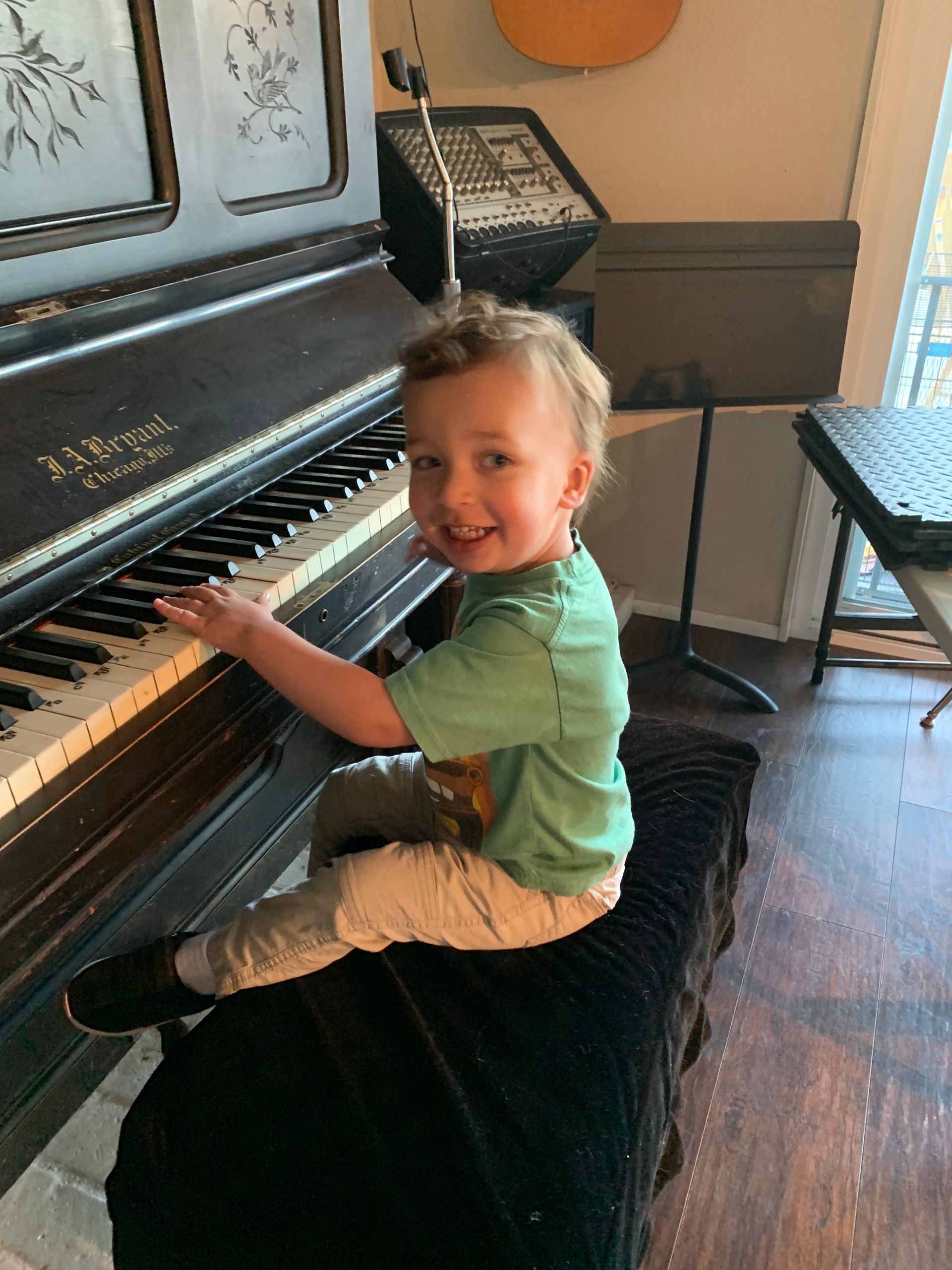 A little boy is sitting on a bench playing a piano