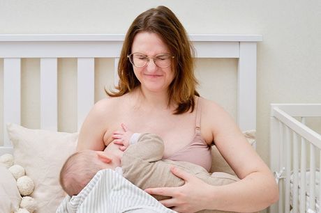 Eine Frau stillt ihr Baby auf einem Bett.