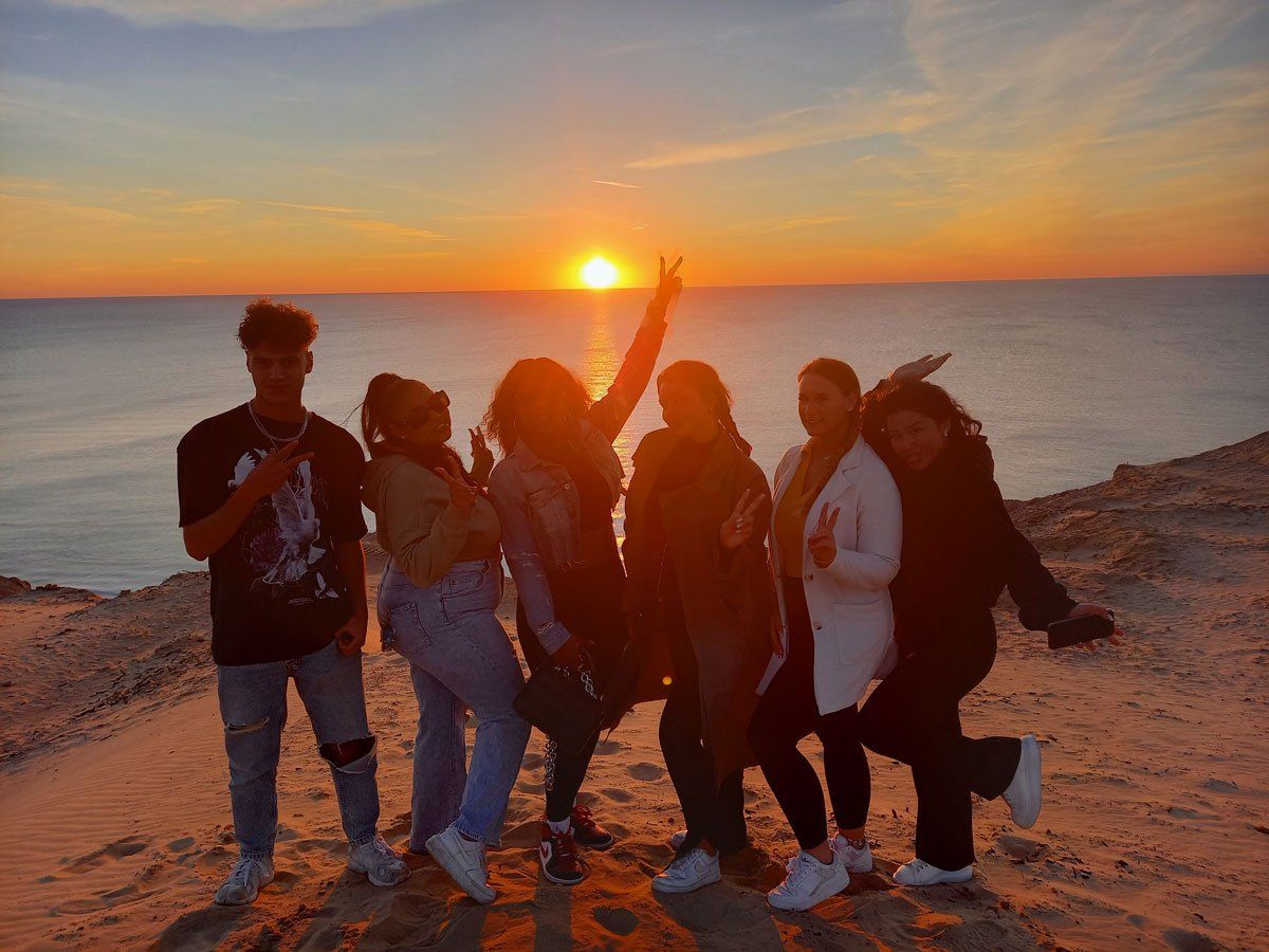 Eine Gruppe von Menschen posiert bei Sonnenuntergang an einem Strand für ein Foto.