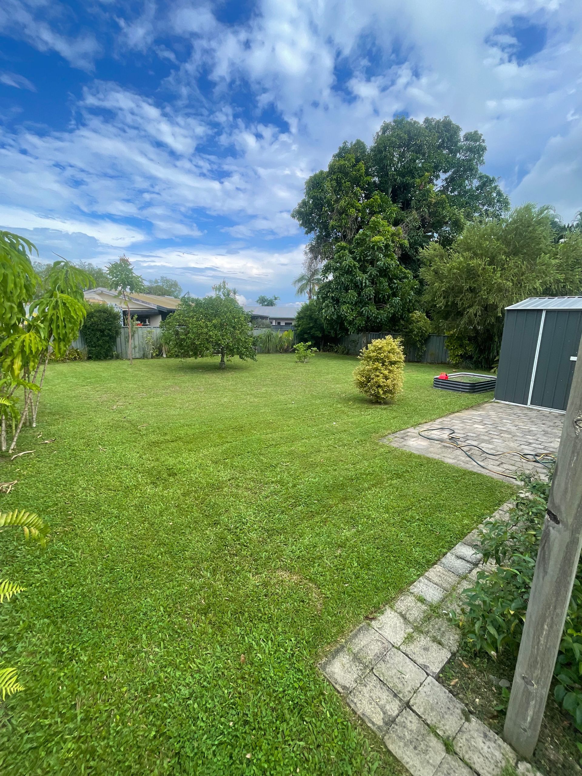 Green Lawn in Backyard, Trees, Blue Sky, Clouds, Stone Path, Shed — Lads Lawns & Gardens in Bentley Park, QLD