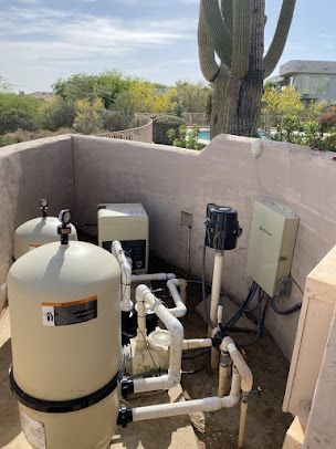 A swimming pool filter is sitting on top of a wall next to a cactus.